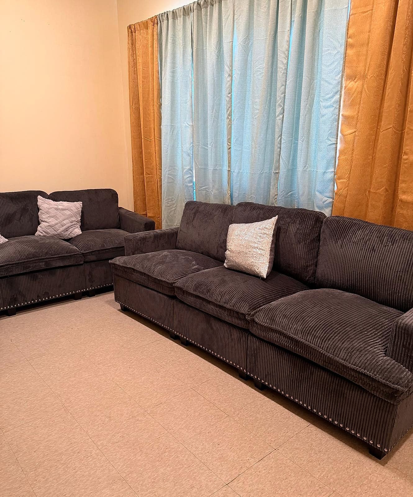 Warm living room space featuring two full-sized sofas, soft lighting, and layered window curtains